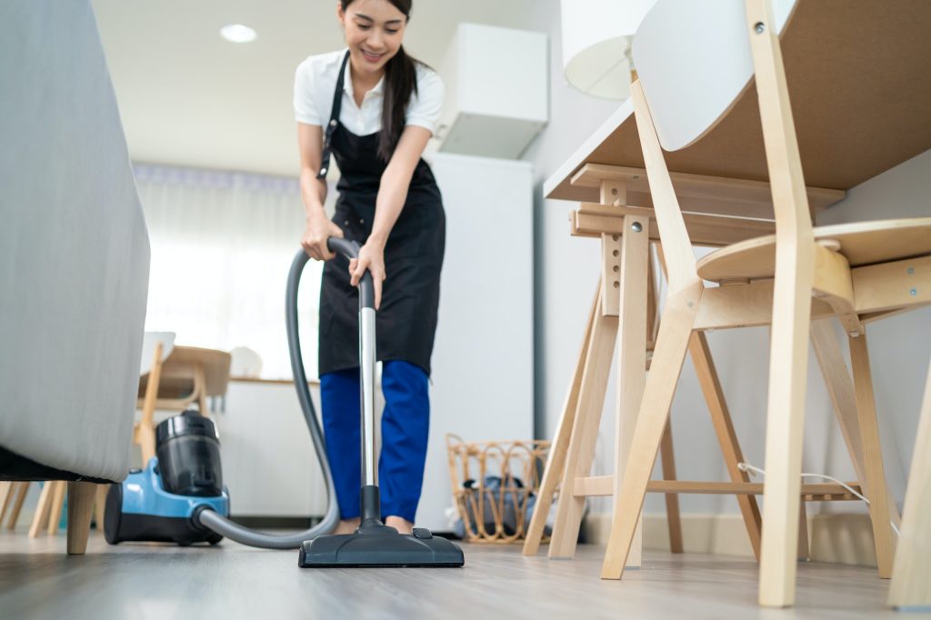 Asian cleaning service woman worker cleaning in living room at home.